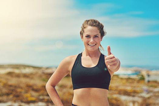 Thumbs up to getting fit in nature. Shot of a sporty young woman showing thumbs up outdoors.