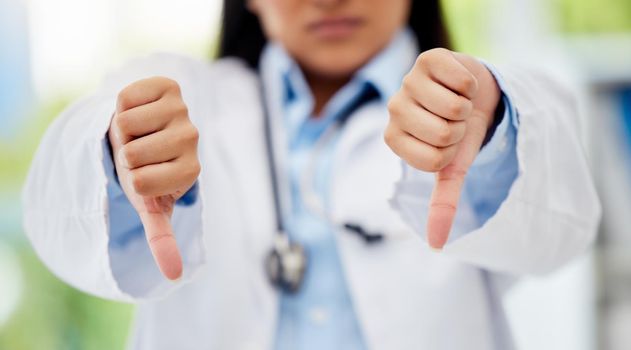 Doctor with thumbs down hand sign in healthcare hospital or lab for fail, poor health insurance or death statistics. Zoom of unhappy, bad loss or loser hands emoji icon of a healthcare professional