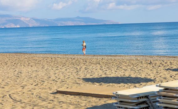 Empty beach with sun loungers and umbrellas in the early morning on a sunny day on the Crete island Greece.