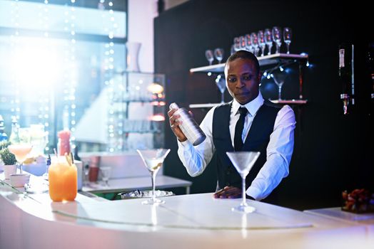 Theres no comparison to his bartending skills. a well-dressed bartender standing behind the counter.