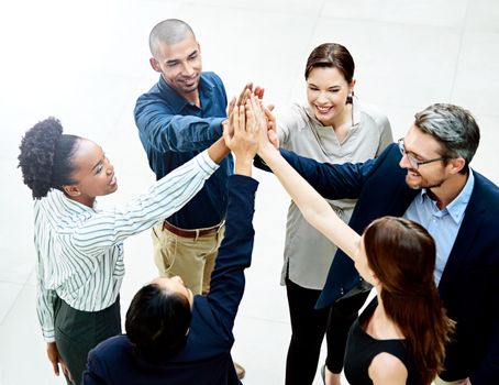 We dont allow negativity in this office. High angle shot of a group of businesspeople giving each other a high five in the office.