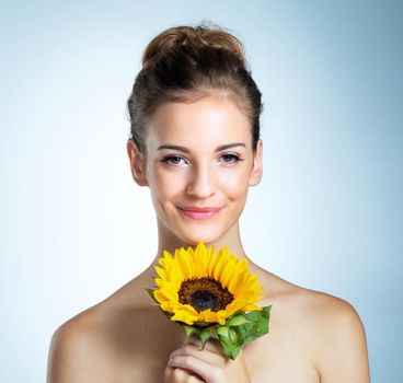 Soft and delicate like a flower. Studio portrait of a beautiful young woman holding a sunflower.
