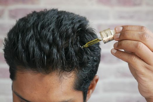 young men applying essential oils on his hair