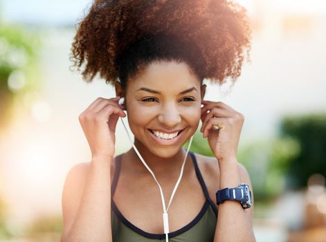 Music gets me going. a young woman inserting her earphones before a run.