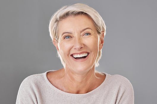 Grooming, skincare and face of happy mature woman laughing against a studio grey background. Senior female feeling fresh, enjoying free time with self care hygiene treatment. Joy after routine pamper