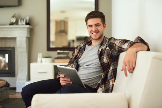 With wireless technology anything is accessible right from your home. a young man relaxing at home with his digital tablet.