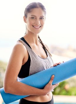 Im headed to yoga class. Portrait of an attractive young woman carrying her yoga mat to class.