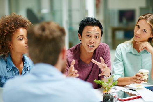 Passionate about business. a group of businesspeople talking together around a table in an office.