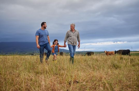 Farmer family walking on a cattle or livestock farm teaching and learning together. Generations of a happy father, grandfather and grandchild bonding on sustainability agriculture land