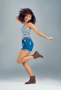 Move to your own rhythm. a carefree young woman posing against a grey background.