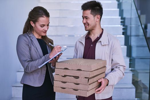 Lunch is delivered. a man making a pizza delivery to a businesswoman at work.