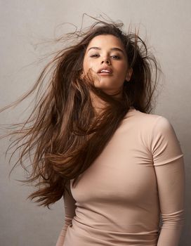 Let your hair express your mood. Portrait of a beautiful young woman posing with the wind in her hair in studio.