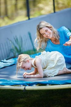 Lets try one more time. a young mother playing on the trampoline with her daughter outside.
