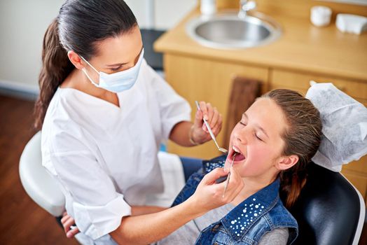 The teeth expert. Shot of a female dentist examining a little girls teeth.