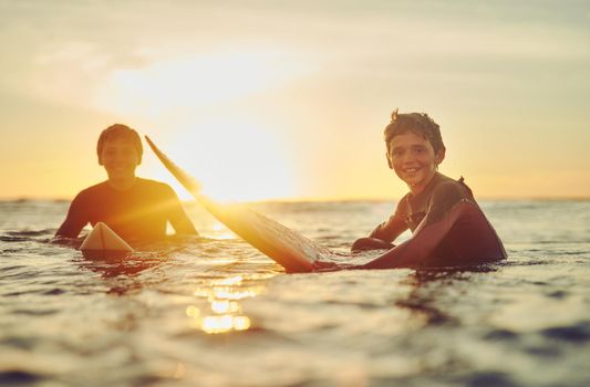 Good vibes happen on the tides. Portrait of two young brothers sitting on their surfboards in the ocean.