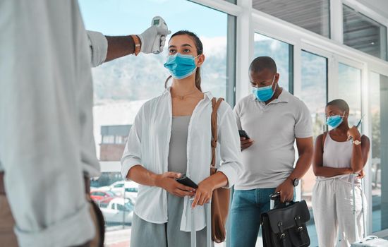 Covid safety traveling, medical doctor with thermometer testing and screening or healthcare doing protocol checkup of people at airport. Travel nurse worker scanning during the corona virus pandemic