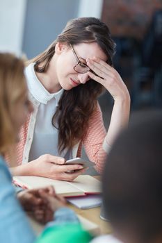 She cant believe it. a worried looking university student reading a text message in class.