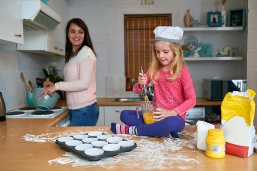 Shes mommys busy little baker. a little girl baking in the kitchen with her mom.