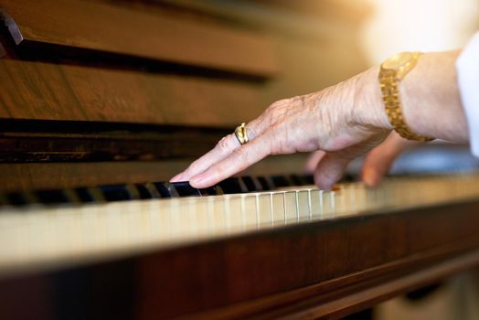 She still remembers the melody. an unidentifiable senior woman playing the piano at home.