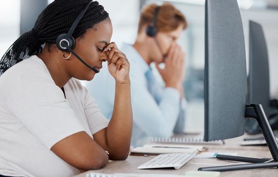 Burnout, stress and headache telemarketing employee working customer support for sales, consulting or call center company. Contact us, help desk and customer service worker in office by computer