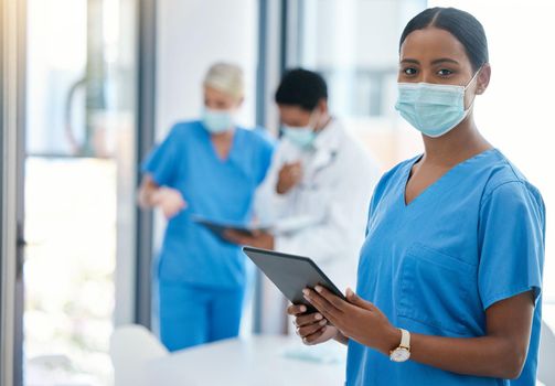 Healthcare, doctor or a nurse on a tablet, consulting in a hospital boardroom. Medical workers meeting to consult, communication online. Covid management and teamwork, doctors wearing surgical masks.