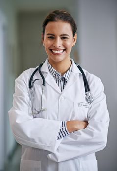 The doctor will see you now. Portrait of a cheerful and confident young doctor crossing her arms.