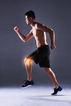 Running through the pain. Full length shot of a young man in the studio with cgi highlighting his knee injury.