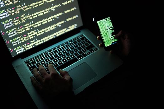 No code is uncrackable. an unidentifiable hacker using a laptop late at night.