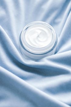 Luxury face cream jar on blue silk