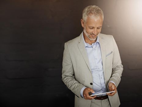 Hes a dynamic man. a mature businessman using a digital tablet.