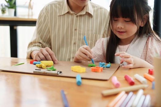 Adorable little girl and father playing with colorful plasticine. Handmade skills training