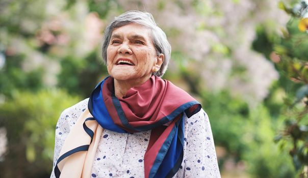 Portrait happy old woman smiling enjoying retirement wearing colorful scarf in beautiful garden