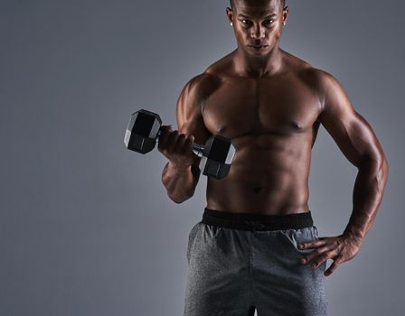 Check me out. Cropped portrait of an athletic young man working up with a dumbbell.