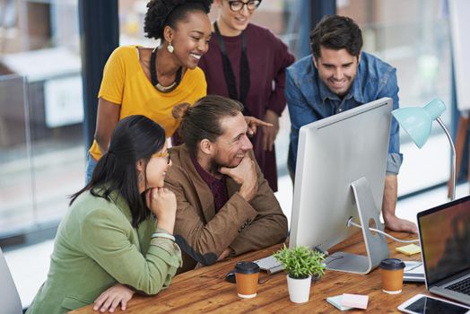 Motivated by their desire to achieve. a group of creative businesspeople looking at something on a computer.