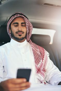 Get moving and get things done. a young muslim businessman using his phone while traveling in a car.
