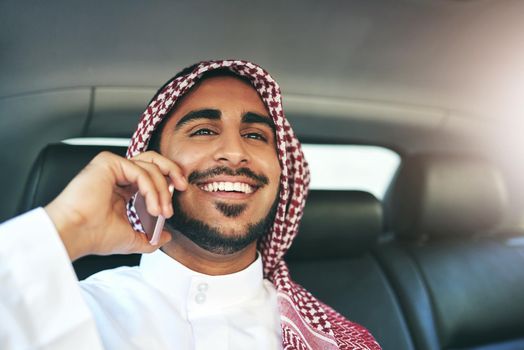 Putting success into motion. a young muslim businessman using his phone while traveling in a car.