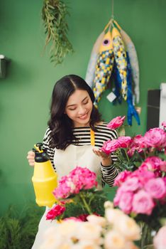 Vietnamese young flower shop owner spraying bouquets