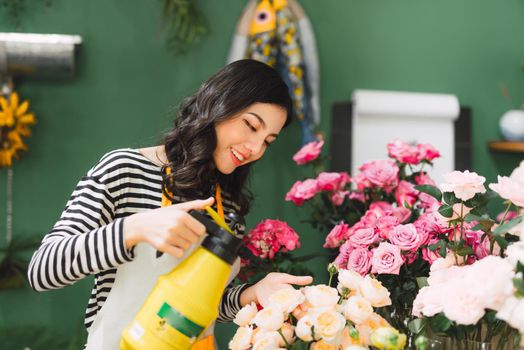 Cute concentrated young female florist  working in flower shop