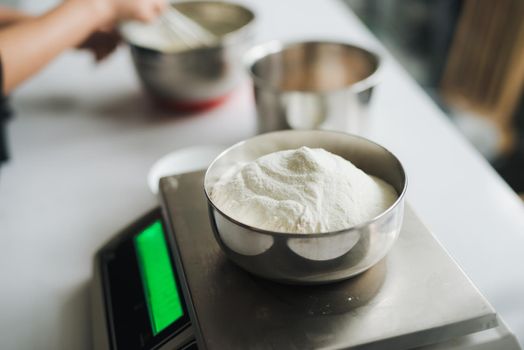 Bakery chef weighing flour on the digital scale