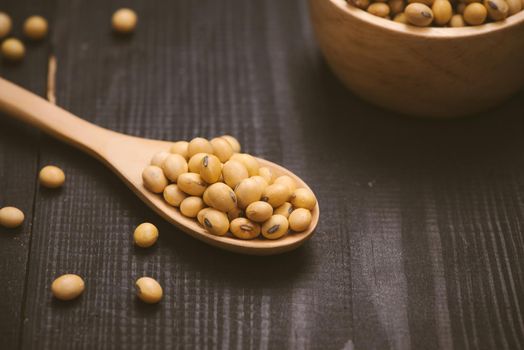 Soy beans in spoon on wooden background