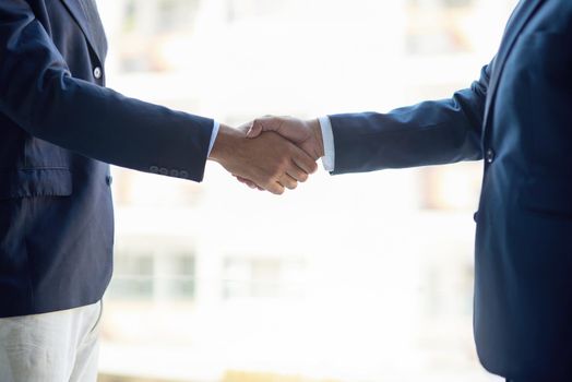 Welcome to the company. two unidentifiable businessmen shaking hands in the office.