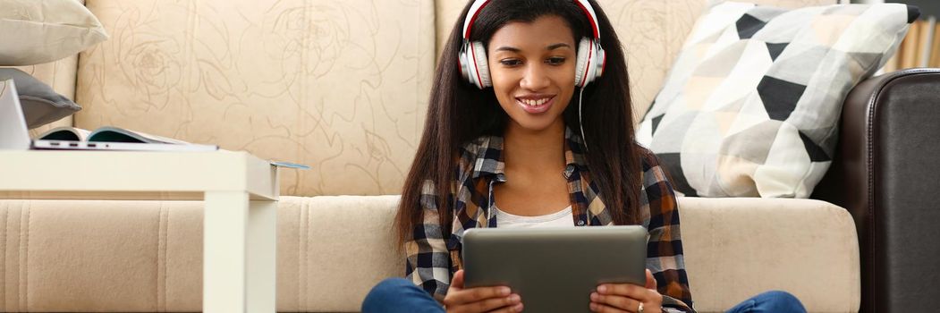 African american woman in headphones looking at digital tablet at home