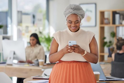Black business woman texting on a phone, smiling while standing in a busy corporate office. Small business owner happy, reading email and positive feedback. Female enjoying her career and success