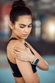 Injury, hurt and shoulder pain for a female athlete holding her painful arm at the gym. Active, fit and athletic woman suffering from muscle inflammation due to an exercise or workout