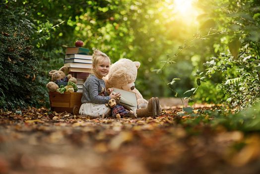 Give them a happy childhood. a little girl reading to her toys while out in the woods.