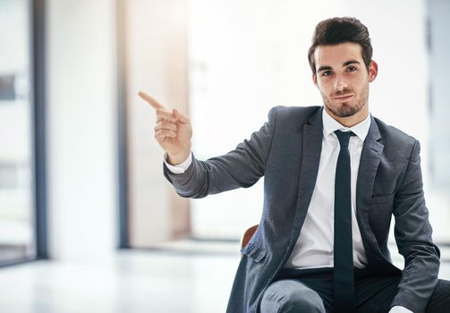 I recommend this copyspace. Portrait of a trendy young businessman pointing to copyspace next to him in the office.