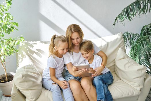 Young mother with kids daughter and boy using digital tablet computer device