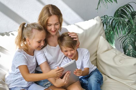 Young mother with kids daughter and boy using digital tablet computer device