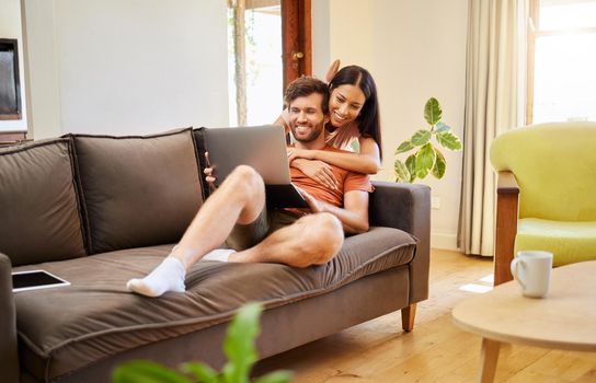 Relax, love and laptop with a couple on the internet at home together on the weekend. Diverse, young and happy man and woman relaxing in the living room and browsing the internet during the day