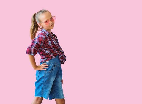 cool kid girl in pink sunglasses posing against pink background